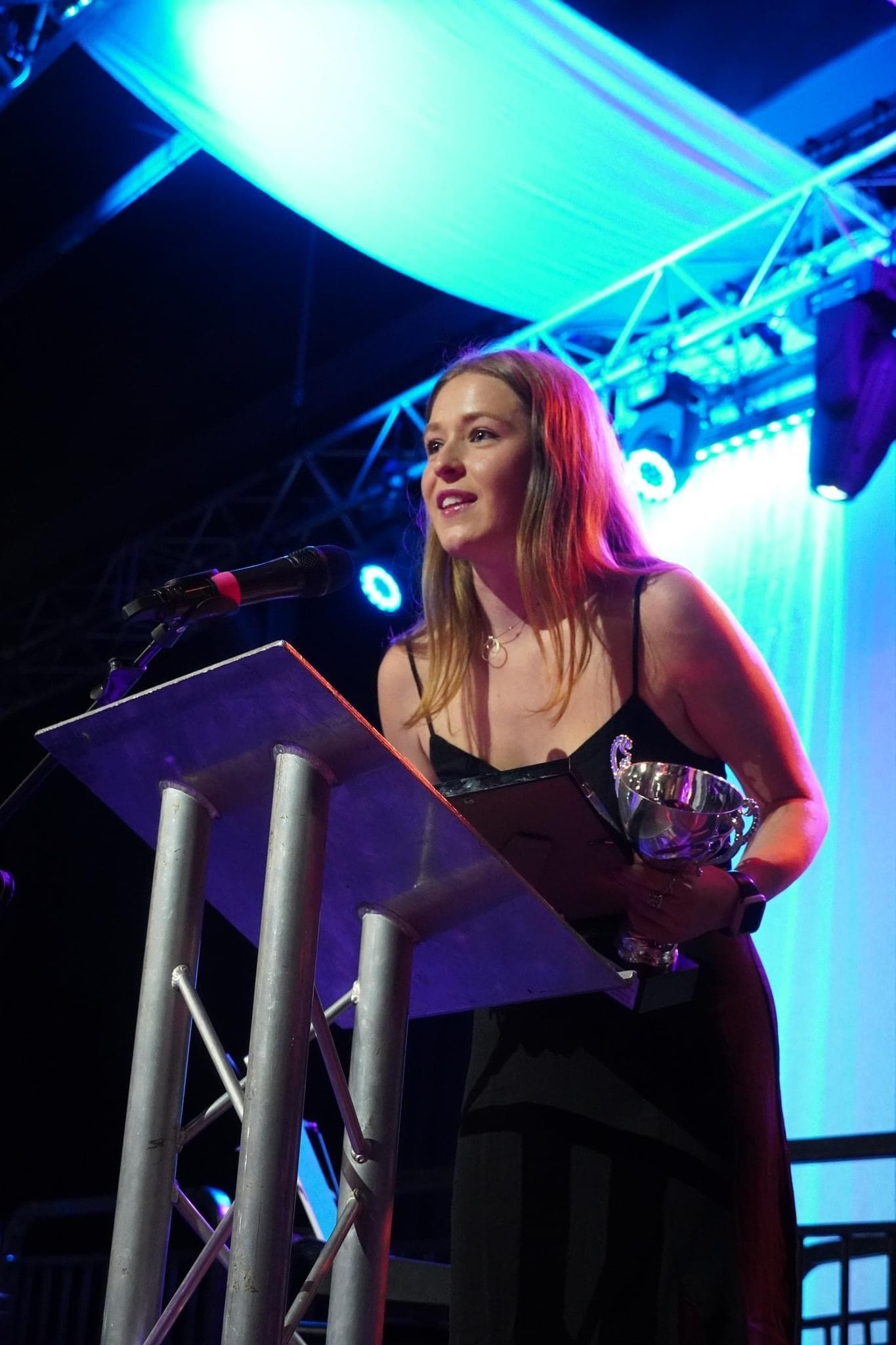Female-presenting individual speaks on the stage holding an award