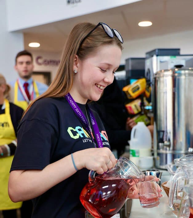 A young woman pours a drink at a community event