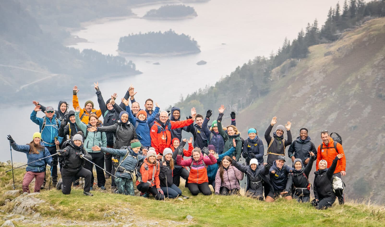 A photo of a group on a hill against a picturesque background of a lake and nature